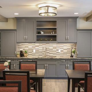 A modern kitchen with gray cabinets, mosaic backsplash, and dining area.