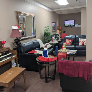 A cozy living room with a piano, sofas, and holiday decorations.