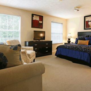 A cozy and well-furnished bedroom with a comfortable bed, dresser, and ample natural light.