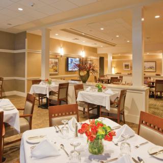 A formal restaurant dining room with elegantly set tables and floral centerpieces.