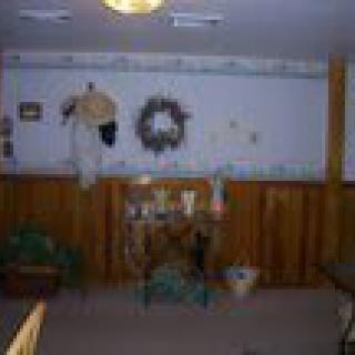 A room interior with wood paneling and decorative items on a shelf, including a wreath on the wall.