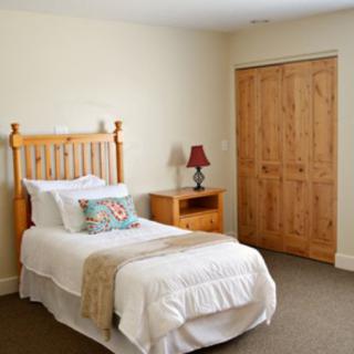 A cozy bedroom with a single wooden bed, bedside table, and lamp.