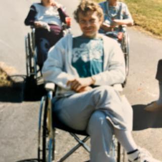 A cheerful group of individuals in wheelchairs enjoying a sunny day outdoors.
