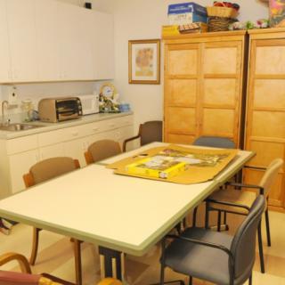 A cozy kitchen space with a dining table surrounded by chairs, featuring cabinets and a toaster oven.
