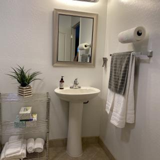 A clean and minimalist bathroom with a pedestal sink, mirror, and neatly arranged towels.