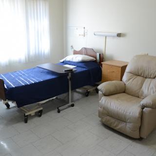 A simple hospital patient room featuring a bed and a recliner chair.