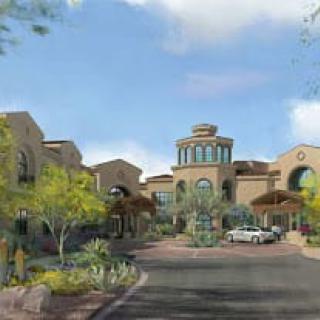 A scenic view of a resort building surrounded by desert landscape and greenery under a clear sky.