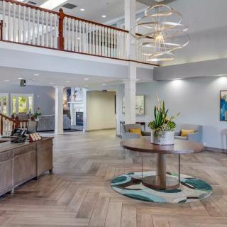 A spacious and modern lobby with elegant furnishings, featuring a large chandelier and wooden flooring.