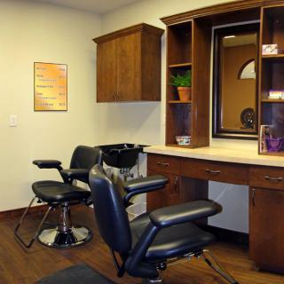 An interior view of a hair salon featuring styling chairs and a vanity with a mirror.