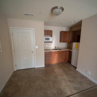 A compact kitchen area in an apartment with wooden cabinets and basic appliances.