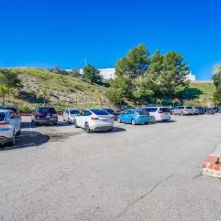 A view of a sunny parking lot filled with various cars under a clear blue sky.