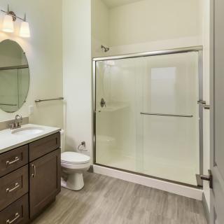 A modern bathroom featuring a glass shower enclosure, vanity with sink and mirror, and a toilet.