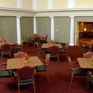 A well-arranged dining room with multiple tables and chairs on a carpeted floor.