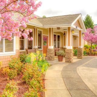 A charming house surrounded by blooming flowers and a well-maintained garden in springtime.