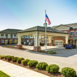 A well-maintained building with a grand entrance, featuring a flagpole and landscaped surroundings.