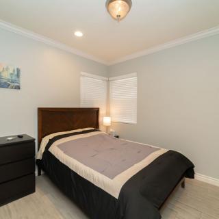 A minimalist bedroom with a neatly made bed and a bedside lamp on a nightstand.