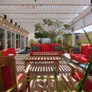 A stylish outdoor patio featuring red cushioned seating and a wooden pergola.