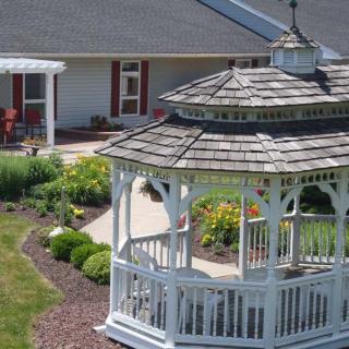 A charming white gazebo surrounded by a well-maintained garden with colorful flowers.