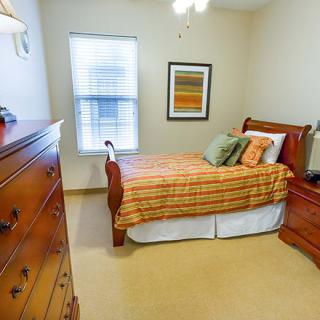A cozy bedroom with warm tones, featuring a wooden bed and dresser.