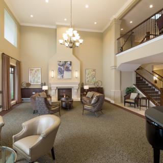 A spacious and elegant living room with a fireplace, chandelier, and comfortable seating area.