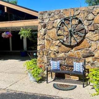A charming outdoor seating area featuring a stone wall with a decorative clock and blooming flowers.