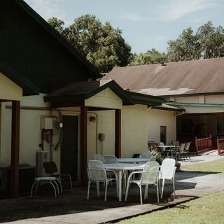 A sunny outdoor patio area with tables and chairs beside a building.