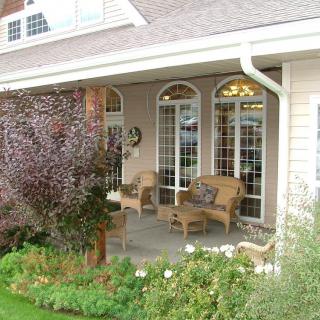 A cozy porch with wicker chairs overlooks a well-maintained garden.