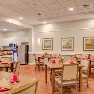 An inviting dining room with neatly arranged tables and chairs, featuring decorative artworks on the wall.