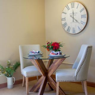 Cozy dining nook with a round table, elegant chairs, and a decorative wall clock.