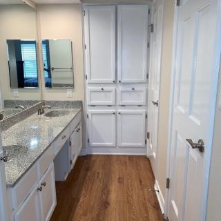 A modern bathroom with granite countertops and ample storage.
