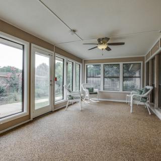 A spacious sunroom with large windows, a ceiling fan, and comfortable seating.