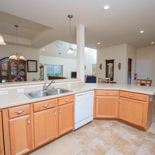 A modern open-concept kitchen with wooden cabinetry and a large countertop featuring a built-in sink and dishwasher.