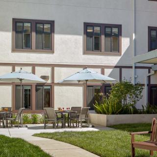 A serene outdoor patio area with tables, chairs, and umbrellas adjacent to a building.
