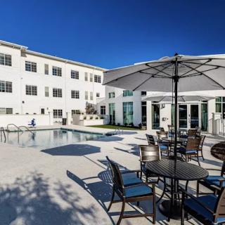 A modern residential complex with a swimming pool and outdoor seating area on a sunny day.