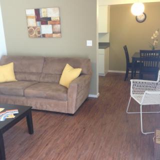 A cozy living room with a brown sofa, yellow pillows, and adjacent dining area.