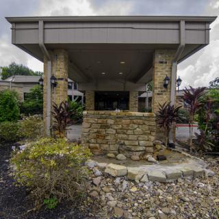 Entrance of a building with stone walls and surrounding greenery.