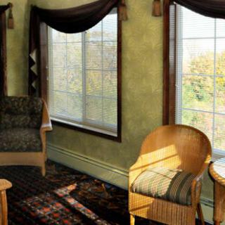 A cozy living room with chairs and large windows letting in sunlight.