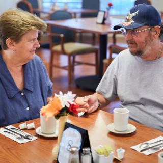 An elderly couple enjoys coffee and conversation at a restaurant.