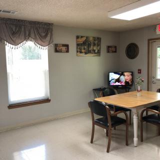 A small room with a table and chairs, featuring a TV and wall decorations.