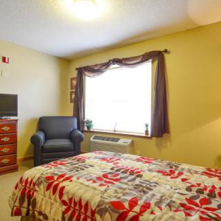 A cozy bedroom with a colorful bedspread, an armchair, and a television.