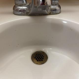 A bathroom sink with a metallic faucet and drain.