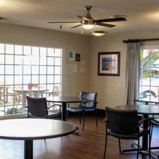 A cozy indoor seating area with round tables, chairs, large windows, and wall art.