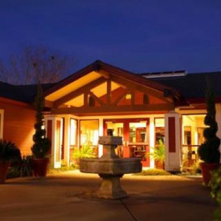 A warmly lit building entrance with a central fountain at night.