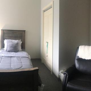 A minimalist bedroom featuring a single bed and a comfortable chair.