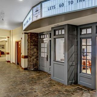 A quaint theater entrance inside a building with a marquee displaying 'LET'S GO TO THE...'.
