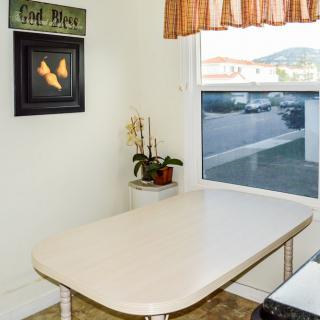 A cozy kitchen corner with a table, plant, and wall art by the window.