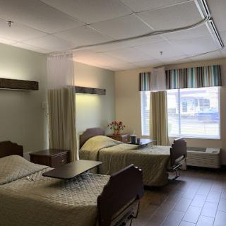 A shared hospital room featuring two patient beds and ample natural light from the window.