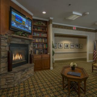 A cozy lounge area featuring a fireplace, television, and bookshelf.