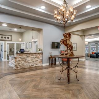 A spacious and elegantly decorated lobby featuring a chandelier and a central sculpture.