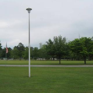 A park scene with a lamp post, trees, and a flag in the distance.